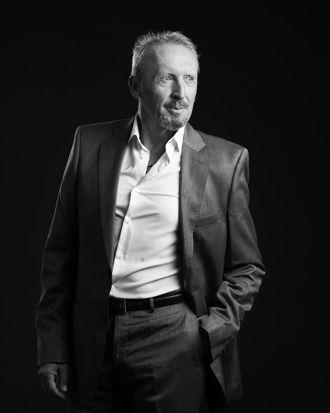 Retrato en blanco y negro de Paco Gumiel con traje y la mano en el bolsillo, mirando fuera de cuadro